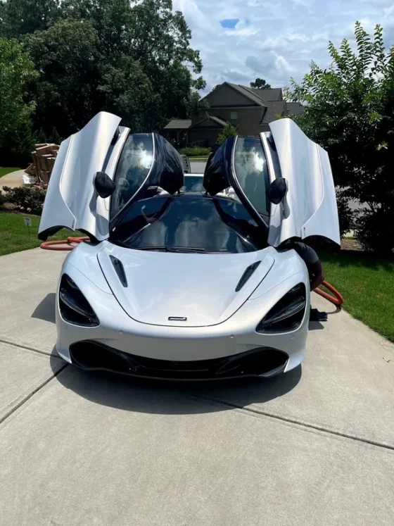White McLaren with its dihedral doors raised after a mobile detail