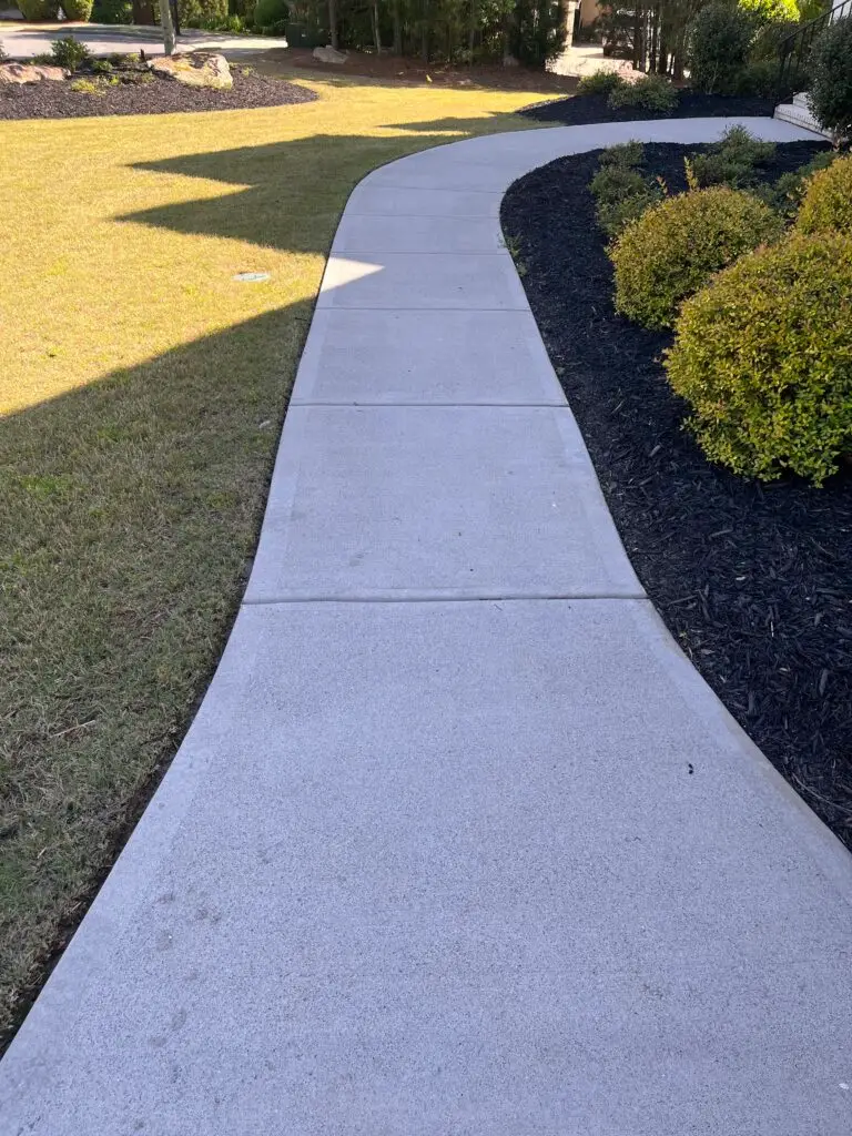 Freshly pressure-washed concrete walkway curving past a green lawn at a metro Atlanta home
