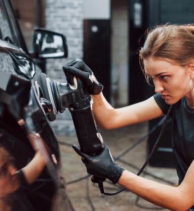 Detailer polishing a car door panel with a machine polisher