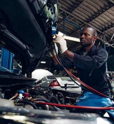 Technician working under the hood of a car in a service bay